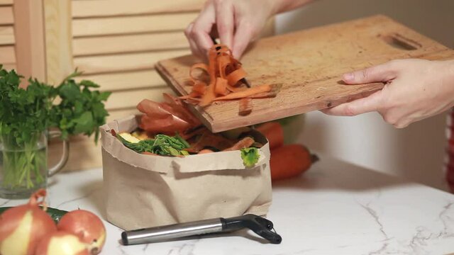 Woman throws vegetable peeling, scraps in compost paper eco bag. Food waste reduce. Sorting of household waste, composting. Zero waste lifestyle. Collecting of food waste in trash-bag for recycling