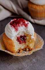 Delicious berry cupcake with frosting and jam on rustic table cut in half