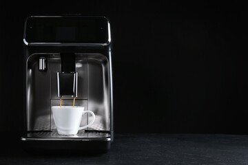 Making coffee with modern espresso machine on grey table against black background. Space for text