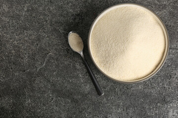 Semolina in bowl and spoon on grey table, flat lay. Space for text