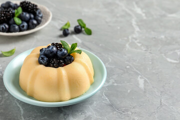 Delicious semolina pudding with berries on light grey table, space for text