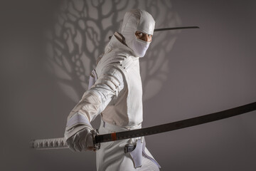 man in white ninja clothes in the studio on a black background