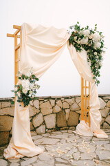 Wedding arch with floral decor stands on an observation deck strewn with rose petals