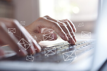 Email concept. Close up of business woman typing on computer keyboard with email icons on virtual...