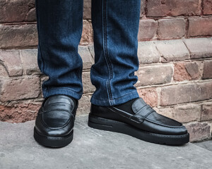 Black shoes on a man standing against a brick wall.