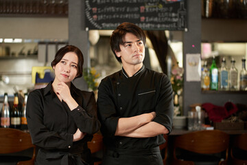 レストランで働く困った様子のアジア人の男女