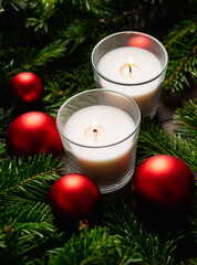 Lighted candle in the green pine branches. Christmas background. Selective focus.