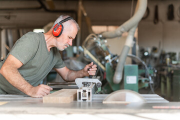 Worker cutting wood with accuracy on a sliding table saw