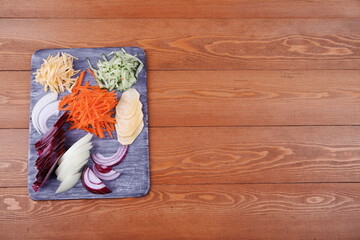 Cook cuts vegetables on a board. the ingredients are beautifully laid out - onion slices, dill. Carrot, Cucumber, Turnip. Cheese. Bright colors. Top view. Food. Still-life. Close-up.Place for text