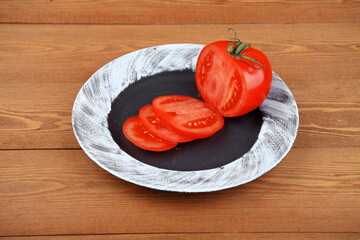 Sliced red tomatoes on a round plate. the ingredients are beautifully laid out vegetables. Bright colors. Top view.Still life is a place for text.