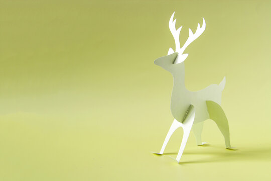 Origami deer made of paper in yellow tones on a beige background.
