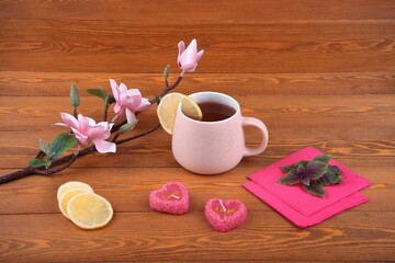 Obraz na płótnie Canvas a cup of tea with lemon for breakfast. On Valentine's Day.An orchid flower on a branch. A green napkin.Spruce branch. candles in the shape of a heart. Still-life. The concept of Christmas for lovers.