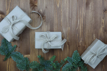 New Year's composition. Christmas gift made of kraft paper, pine cones, fir branches on a wooden background. Top view, flat lay, copy space. Zero Waste Concept