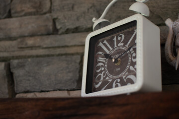 Closeup of a square alarm clock against a brick wall in a modern room