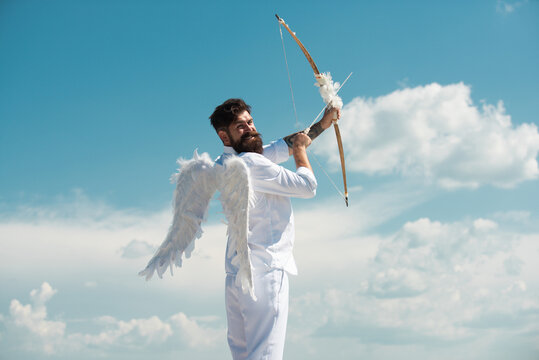 Surprised cupid with wings aiming with bow and arrow on a sky background. Funny valentines day concept. Humor comical concept.