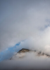 Epic mountain landscape image of Pen Yr Ole Wen in Snowdonia National Park with low cloud on peak and moodyfeel