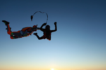 Skydiving. Sunset jump. Two skydivers are in the sky.