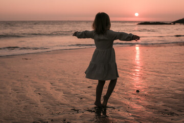 Girl walking on the beach with arms open 