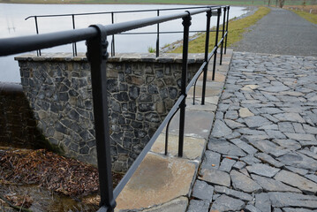 bridge over safety spillway of the dam. stone bridge with natural paving of gray flat stones. on...