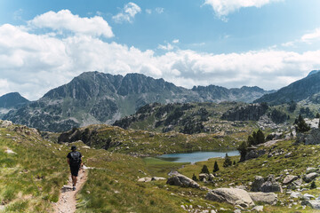 man is walking in the middle of the mountains with a lake in the background