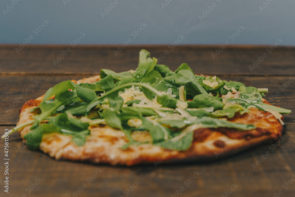 Sticker closeup shot of a homemade thin pizza with spinacon a wooden board