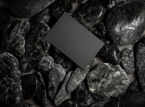 black mock up business card on black stones or galet ,concept of zen spa or sauna branding .