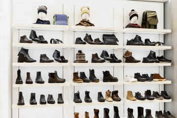 Shoes and accessories on the shelves in the store. Collection of the autumn-winter season. Hats, bags and boots. Front view.