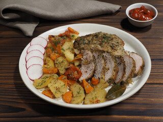 Fried potatoes with carrots and tomatoes, grilled pork chops, slices of steak with spices in a plate, tomato sauce on a dark wooden table. Hot dish with vegetables and meat for lunch, flat layout