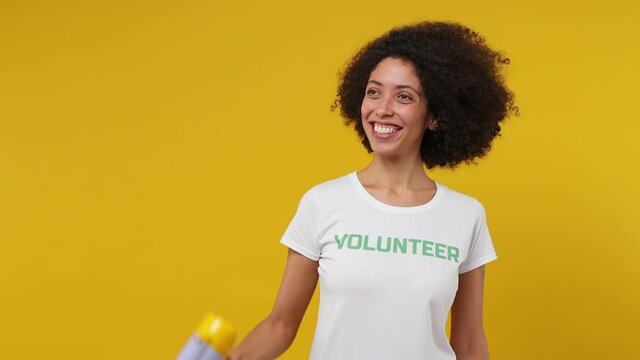 Excited happy young black woman 20s in white t-shirt green title volunteer hold scream in megaphone aside isolated on plain yellow background studio portrait. Voluntary free work help charity concept