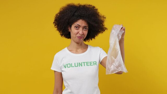Smart young black woman 20s in white t-shirt green title volunteer hold plastic bag say no refuse yes to paper choose eco isolated plain yellow background studio portrait. Stop nature garbage concept