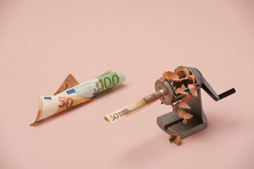 A twisted note in a sharpener with shavings symbolizes inflation and devaluation of money