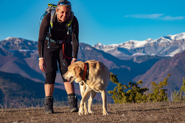 Female hiker and her golden lab dog enjoying a happy hike with amazing view in the French Alps