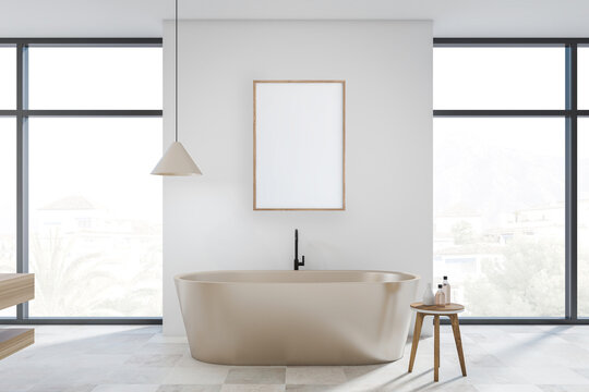 Bright bathroom interior with bathtub, empty white poster, panoramic window