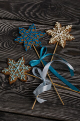 Gingerbread cookies in the shape of a snowflake. Decorated with sugar glaze. Gingerbread cookies on a stick in the shape of a snowflake. Lie on black boards. Close-up shot.