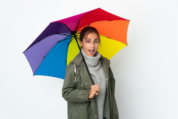 Young woman holding an umbrella isolated on white background with surprise facial expression