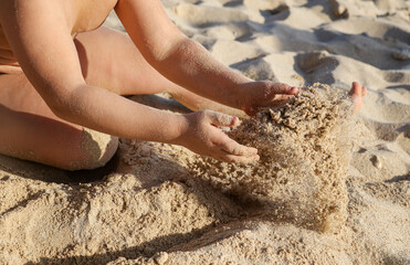 A boy plays in the sand on the beach near the sea.