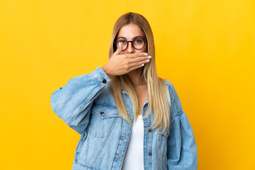 Fototapeta premium Young blonde woman isolated on yellow background covering mouth with hand