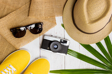 Summer objects with hat, sunglasses, camera with yellow shoes over the wooden background. 