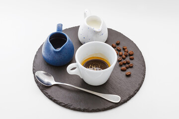 Serving coffee - small white cup, blue coffee pot, teapot, cream in a separate bowl, coffee beans. Isolated