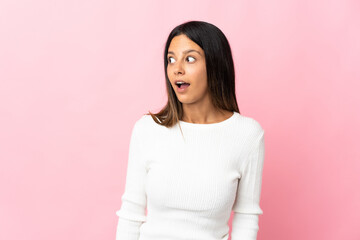 Fototapeta premium Caucasian girl isolated on pink background doing surprise gesture while looking to the side
