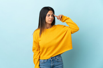 Caucasian girl isolated on blue background making the gesture of madness putting finger on the head