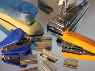 Closeup shot of staples and staplers on a reflective surface