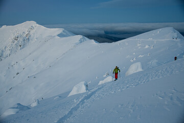 beautiful view of the high snow-capped mountain range and skiers walking along it