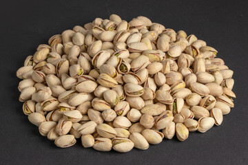 Pile of pistachios in the peel close-up on a dark background.