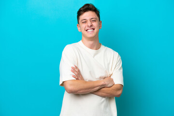 Young handsome Brazilian man isolated on blue background keeping the arms crossed in frontal...