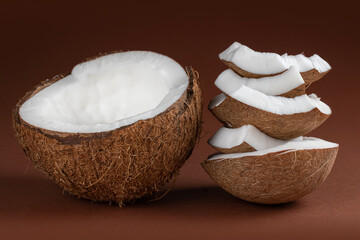 Coconut with half and pieces on brown background