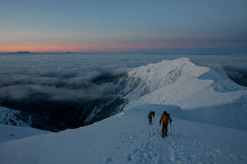 magnificent view of the high snow-capped mountain range and skiers walking along it