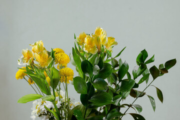 Bouquet of random flowers in a vase against a light green backgr