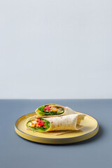 Pair of fresh wrap sandwiches with chicken and vegetables on yellow on grey plate trendy color