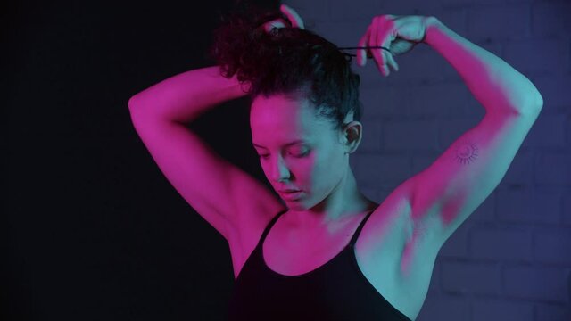 Young woman putting her curly hair in high ponytail before workout